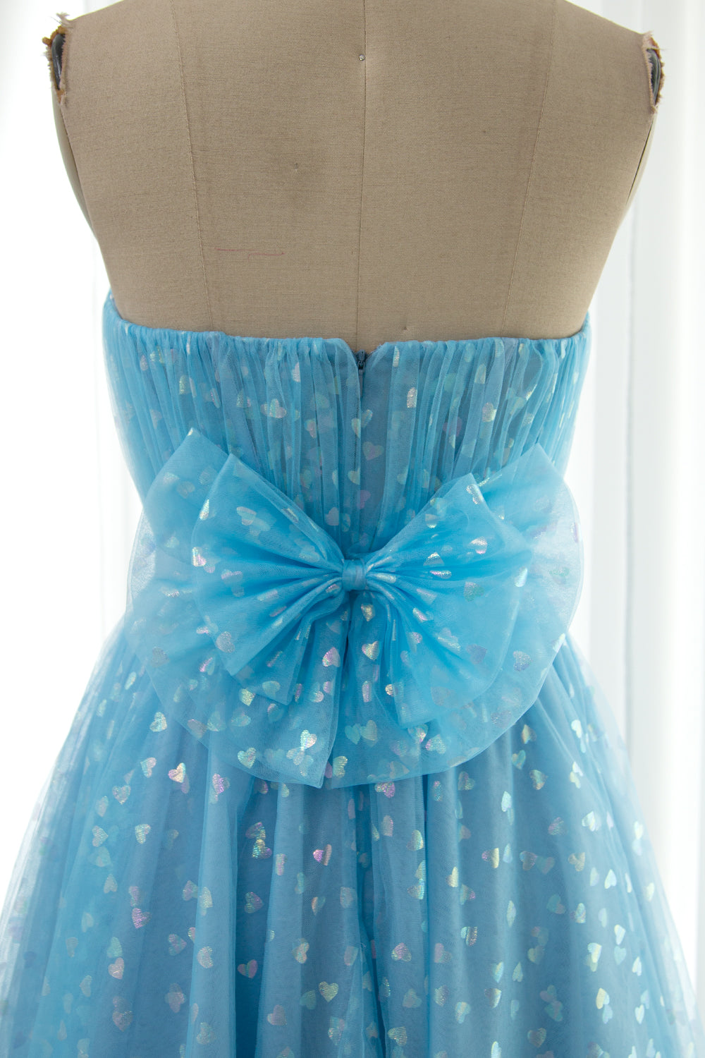 Removable oversized bow detail at back of strapless blue glitter heart tulle midi dress with fitted bodice and flared skirt