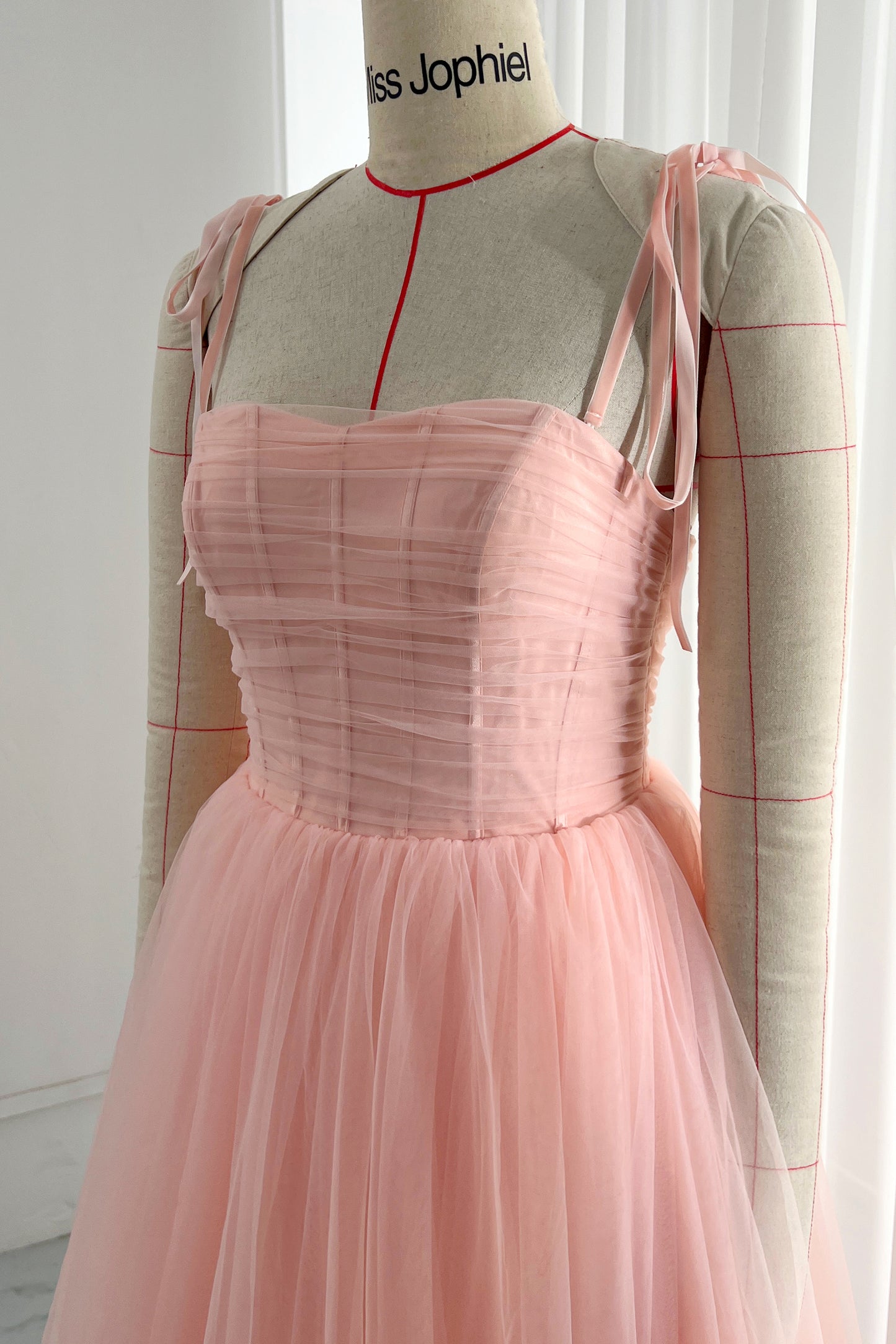 MissJophiel Blush pink tulle midi dress with ruched bodice and delicate shoulder tie straps for a soft romantic style on mannequin