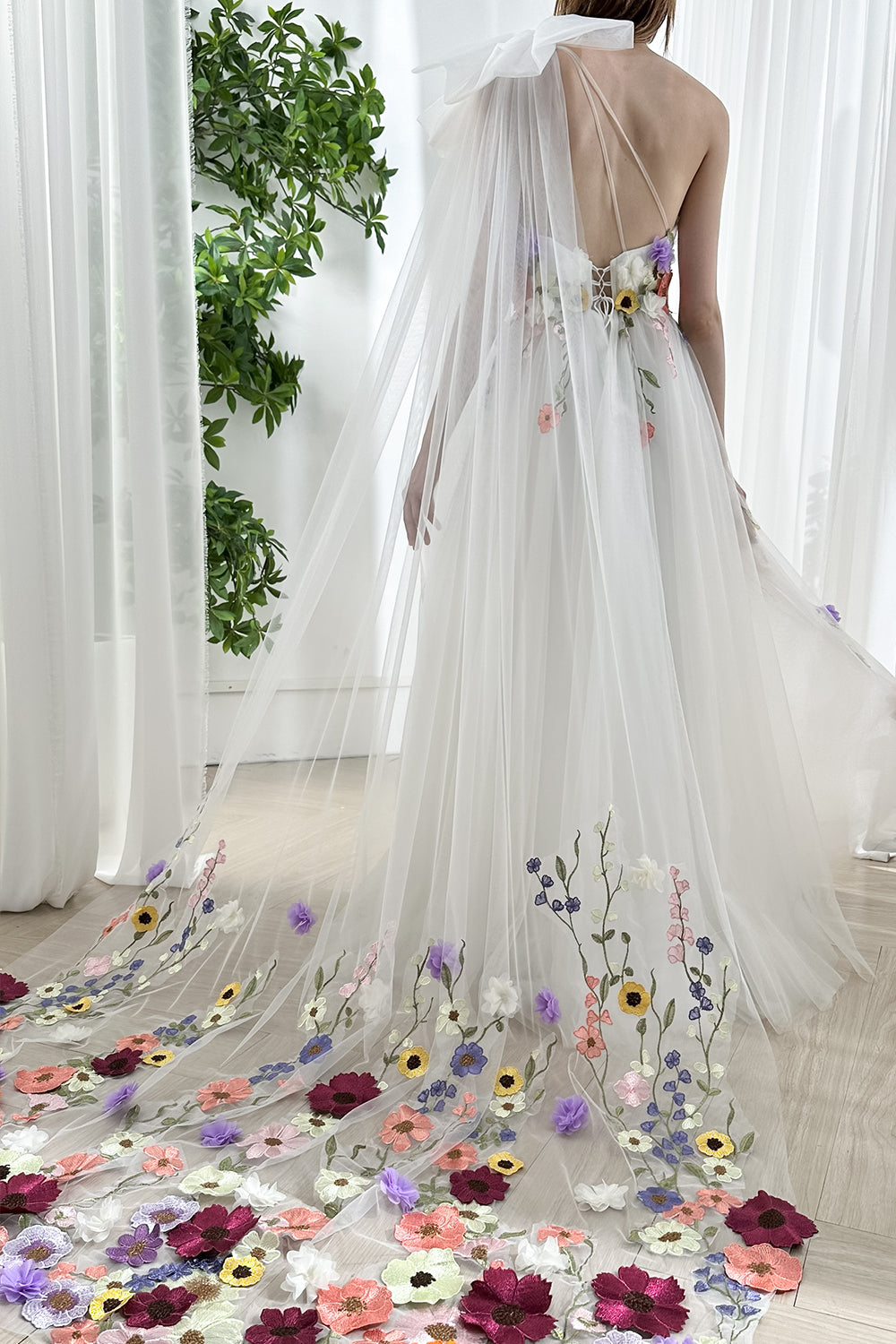 Vestido de novia con un hombro descubierto, apliques florales y cola