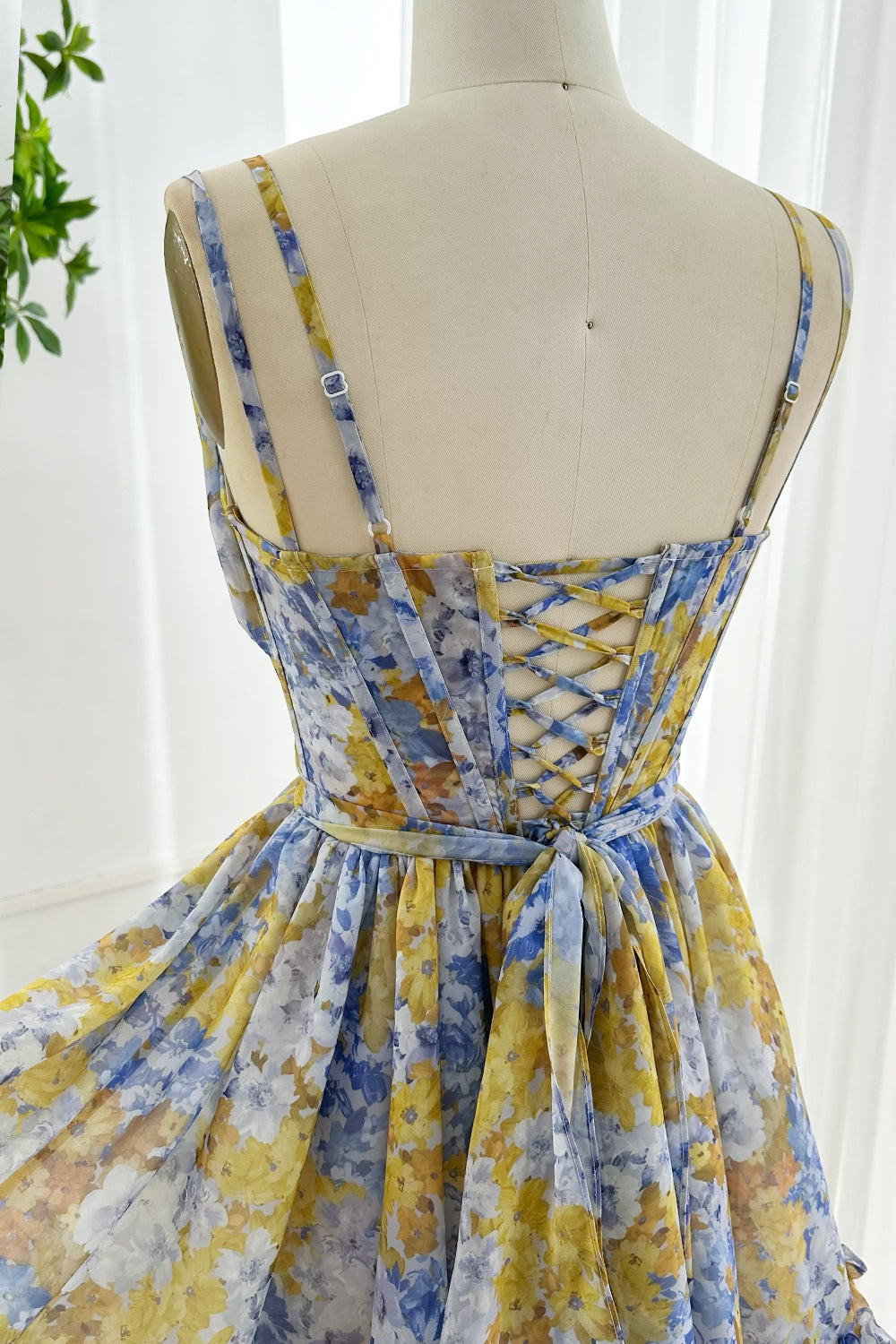 Floral chiffon mini dress close up featuring adjustable shoulder straps and elegant lace-up corset back with tied bow detail