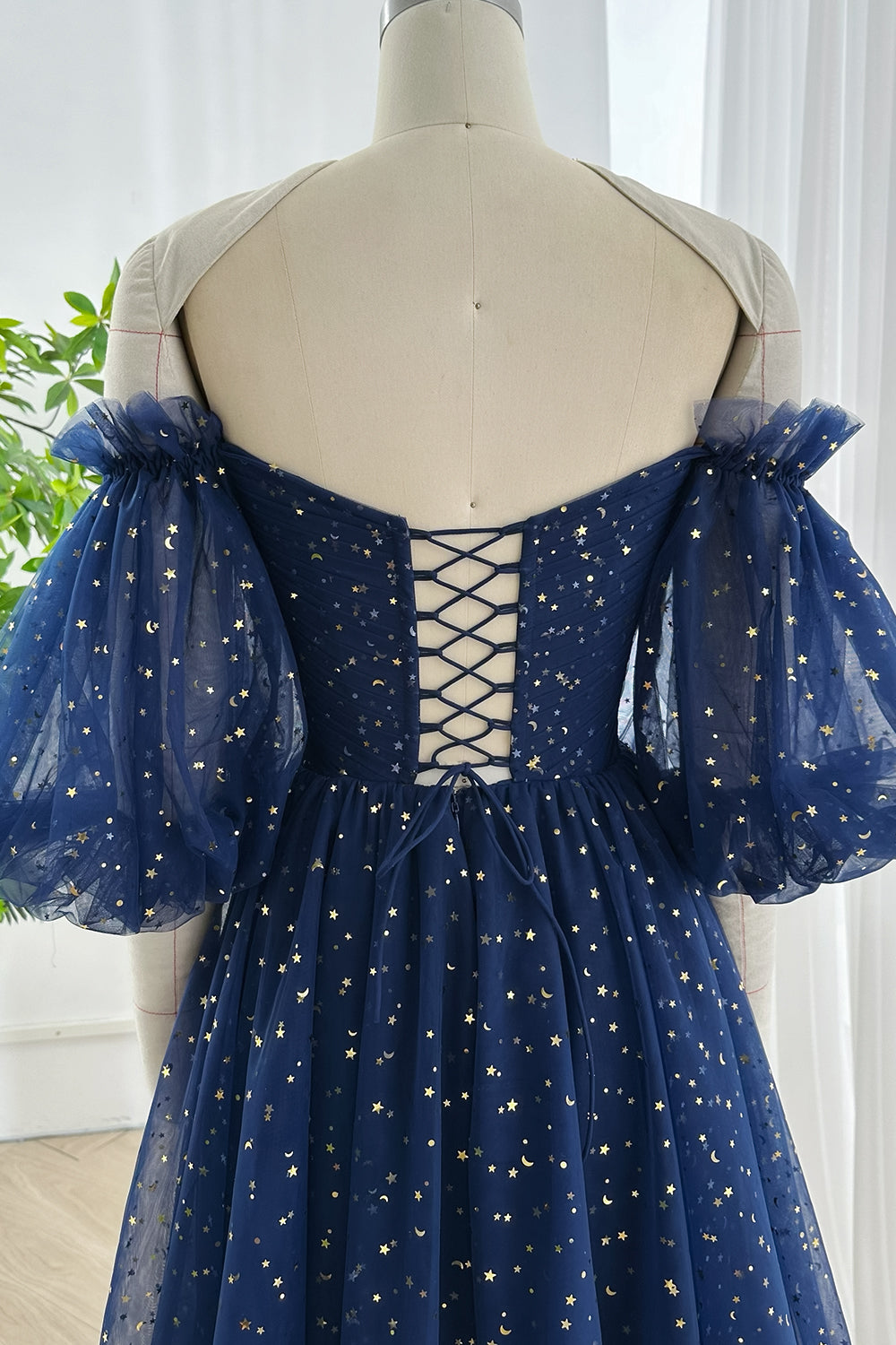 Corset back navy blue star mesh dress decorated with gold moon accents gathered puff sleeves and flowing layered skirt shown in Miss Jophiel workspace