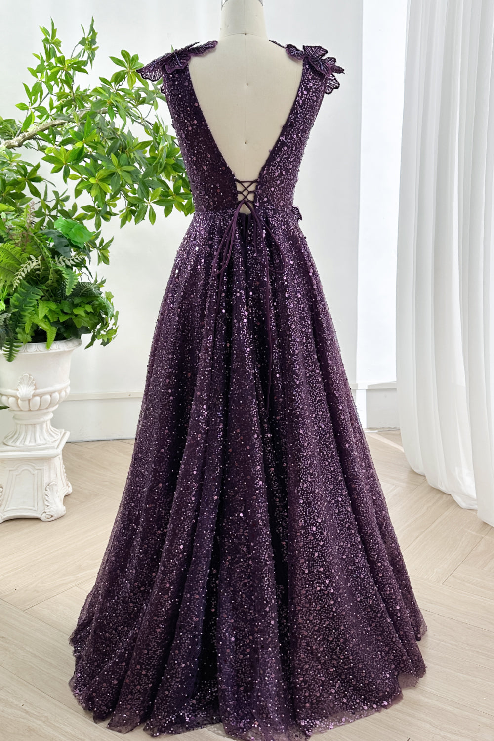 Rear full length view of amethyst sequin ball gown featuring deep open back floral shoulder accents and dramatic sweeping skirt
