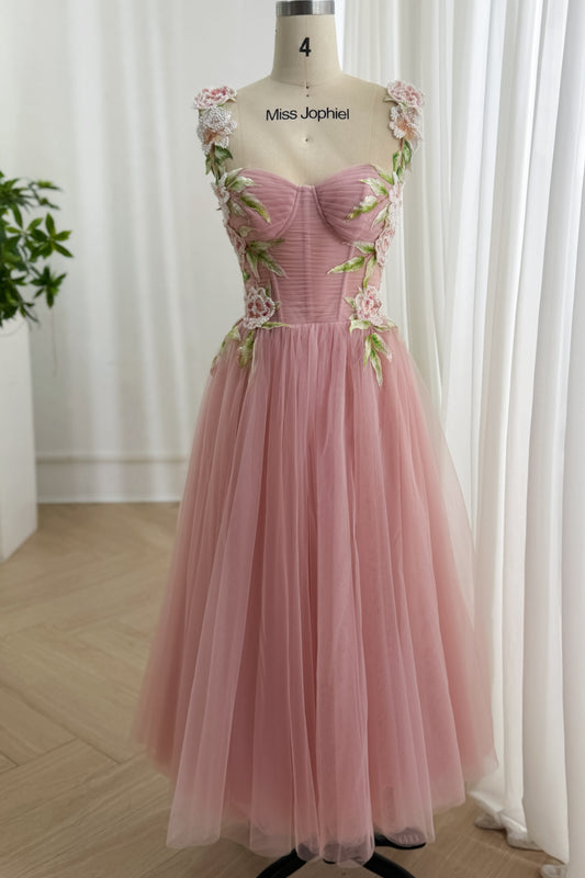 Rose laced-back gown showcases embroidered blossoms, green leaves, sheer shoulder panels, tea-length celebration outfit, aura