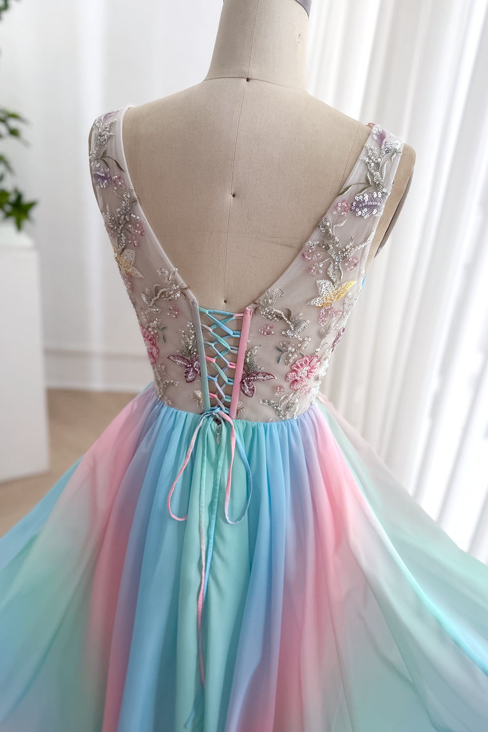 Reverse closeup displays sheer tulle embroidery, sequins, adjustable ribbons, romantic fairytale reception catalog charm glow