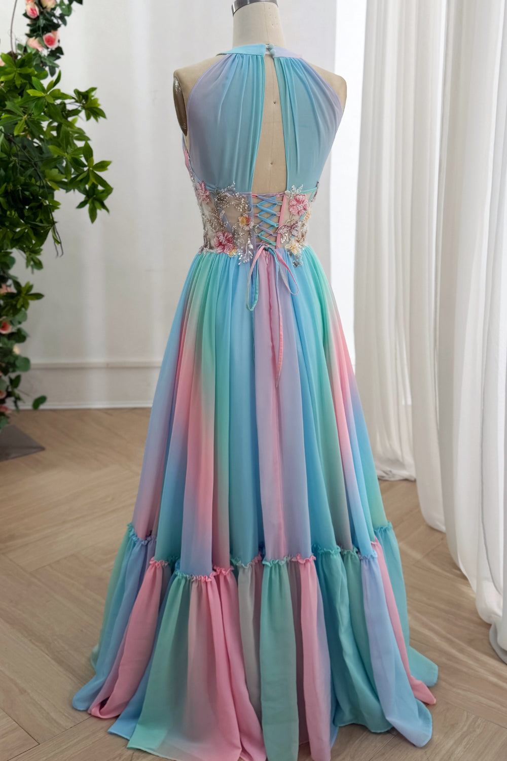 Back angle presents multicolor layered hemline, gathered flounce border, delicate blossom accents during boutique photoshoot.