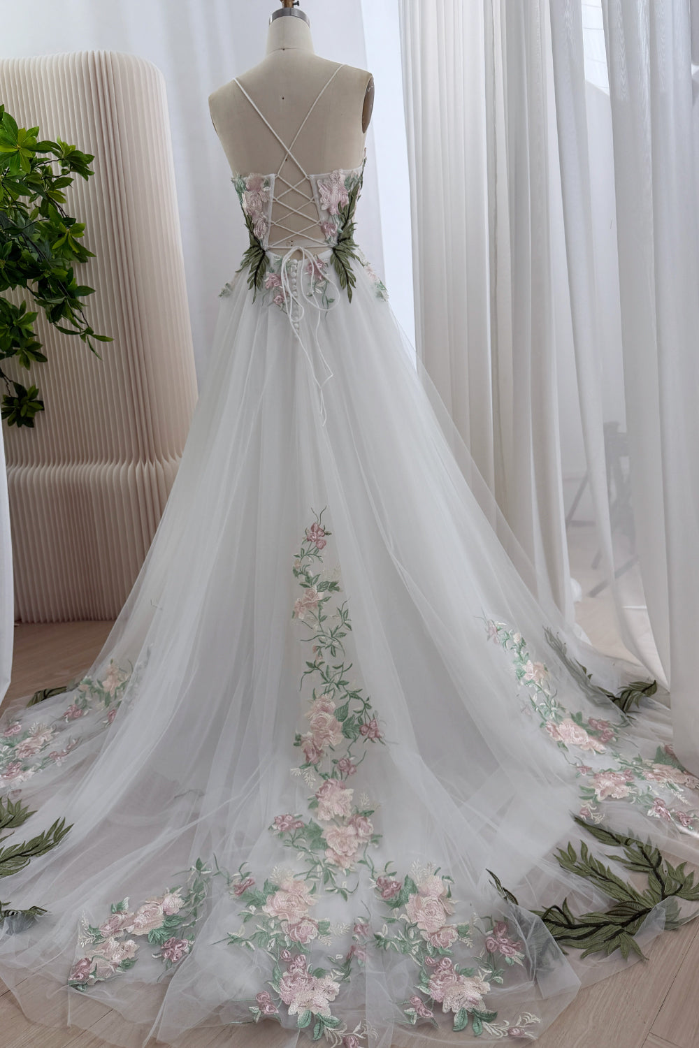 Backward perspective emphasizes lace-up closure, low scoop, blooming border, elongated trailing extension, symmetrical layout