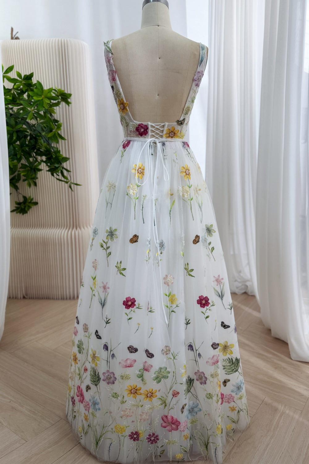 Rear perspective features deep open back, lace-up fastening, floral shoulder bands, gathered train, enchanting garden detail.