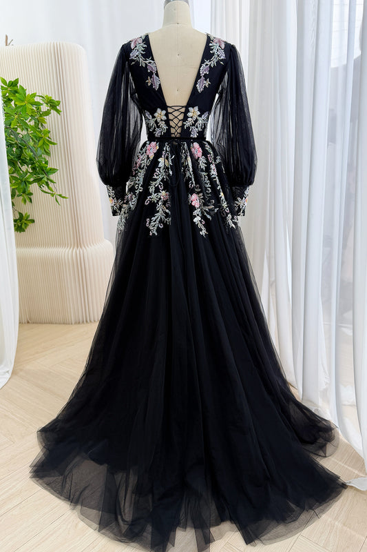 Back view of a black tulle formal gown showing a deep V-back with corset lace-up detail and floral sequin embroidery