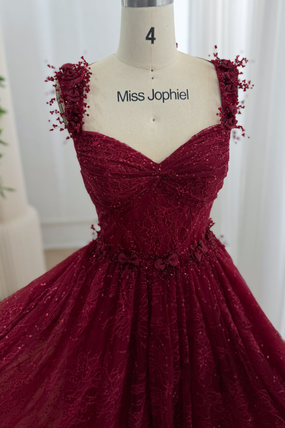 Front detail of the burgundy sweetheart dress showing sequined floral lace and three-dimensional flower accents