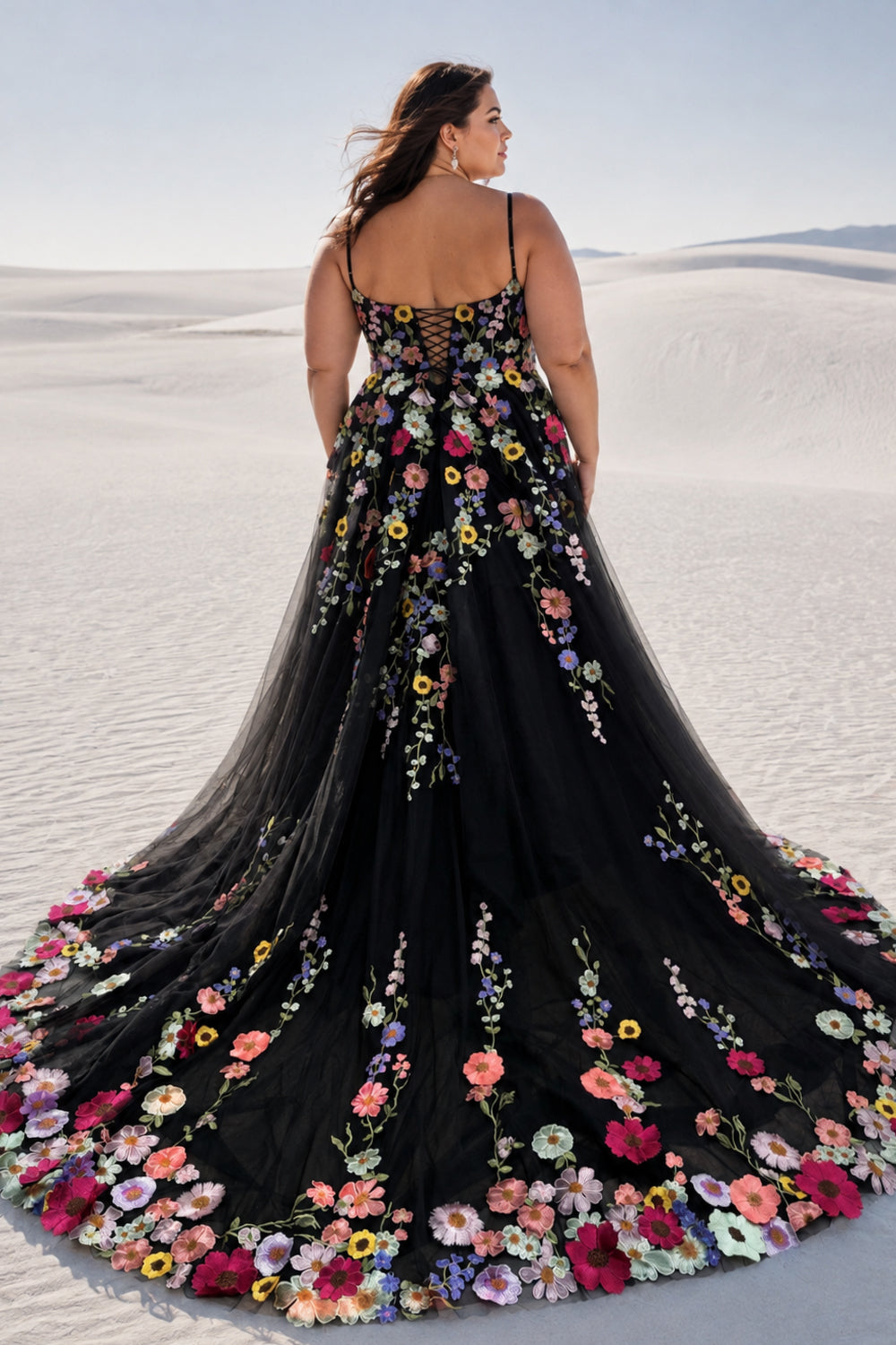 Back view of a plus size model in a desert wearing a black floral tulle gown showing the gorgeous long train.