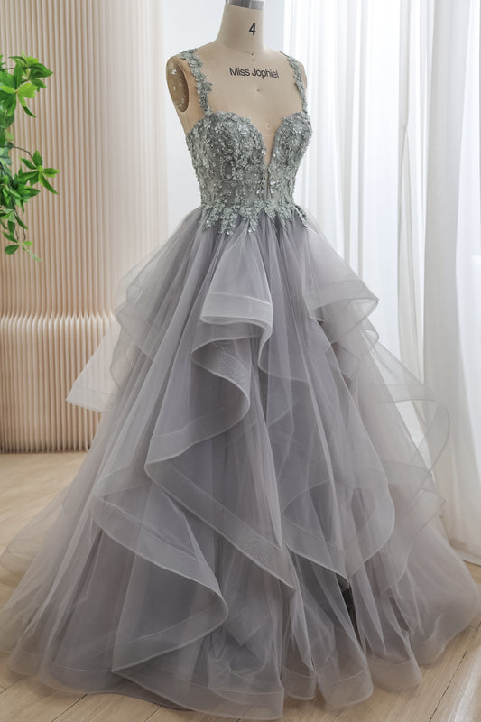 Angled front view of a silver-gray floral corset gown with embellished shoulder straps and a full floor-length tulle ruffle skirt.