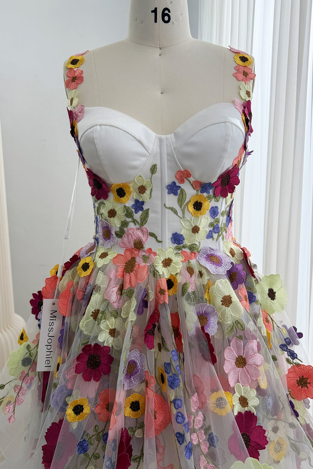 Front close-up of the white sweetheart bodice and multicolor flower appliqués on the tulle skirt