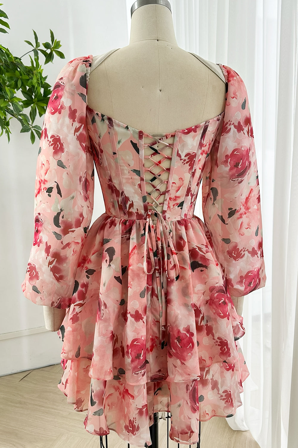 Back view pink floral mini dress featuring lace-up corset closure, chiffon ruffle skirt and long puff sleeves ideal for bridal showers and birthdays