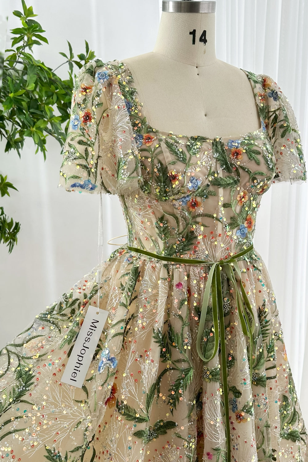 Handmade floral embroidered nude base cocktail dress with puff sleeves sequin sparkle details closeup neckline and waist ribbon sash