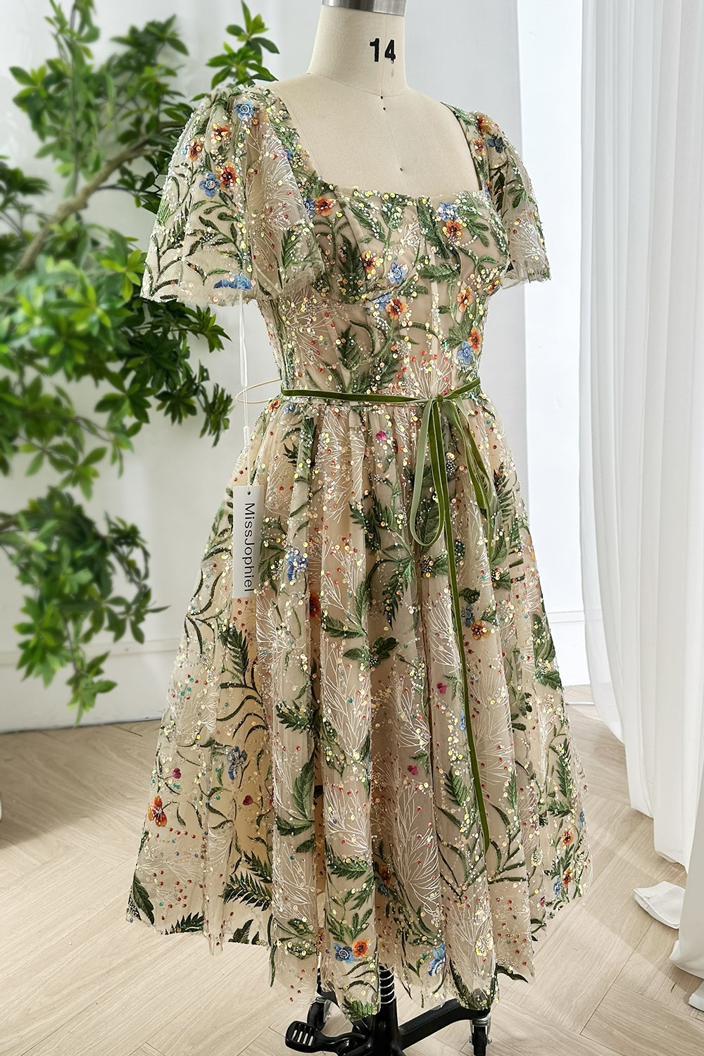 Romantic fairytale inspired embroidered floral sequin tulle midi gown with puff flutter sleeves lace up back styling displayed on mannequin