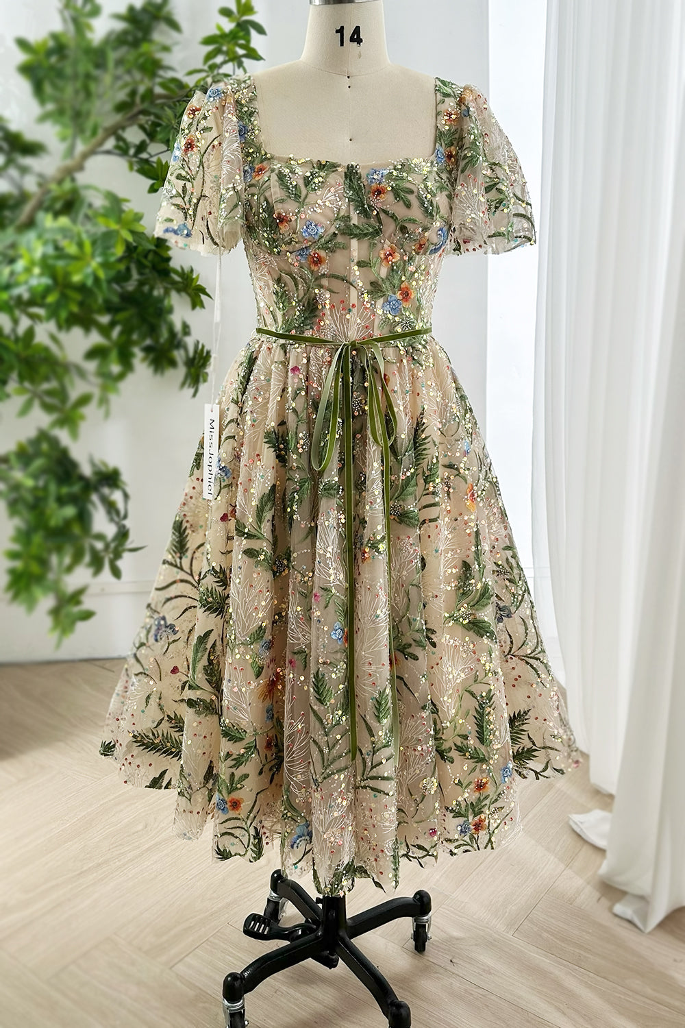 Romantic floral embroidered sequin tulle midi dress with puff sleeves square neckline and green ribbon waist shown on mannequin front view