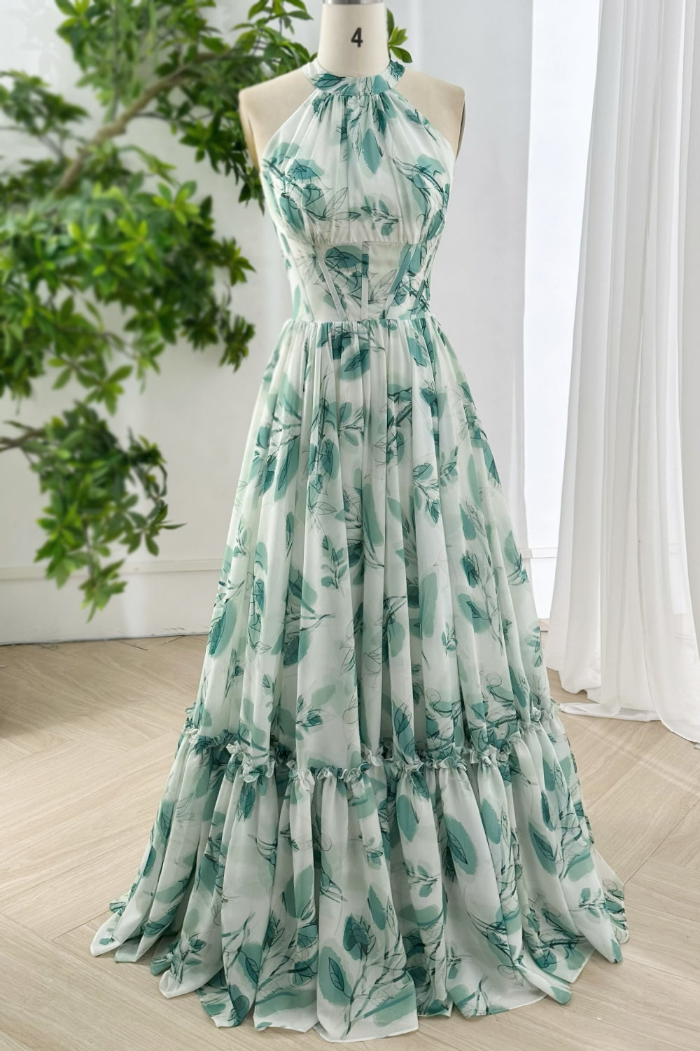 Full length flowy chiffon halter gown in botanical green print with gathered waist and ruffled skirt for evening formal events
