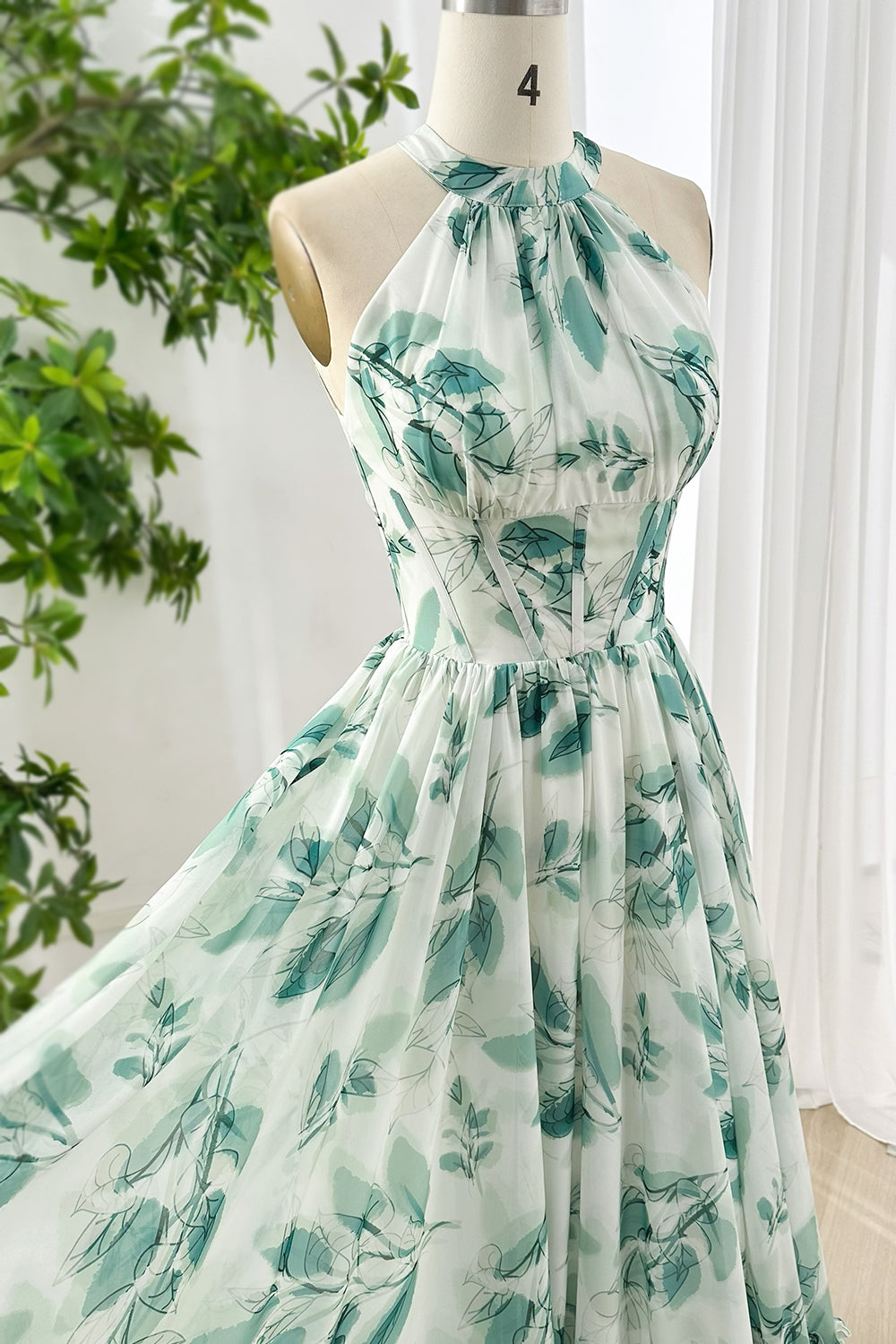 Elegant sleeveless halter maxi dress with green leaf print chiffon fabric and corset-inspired bodice for wedding guest attire