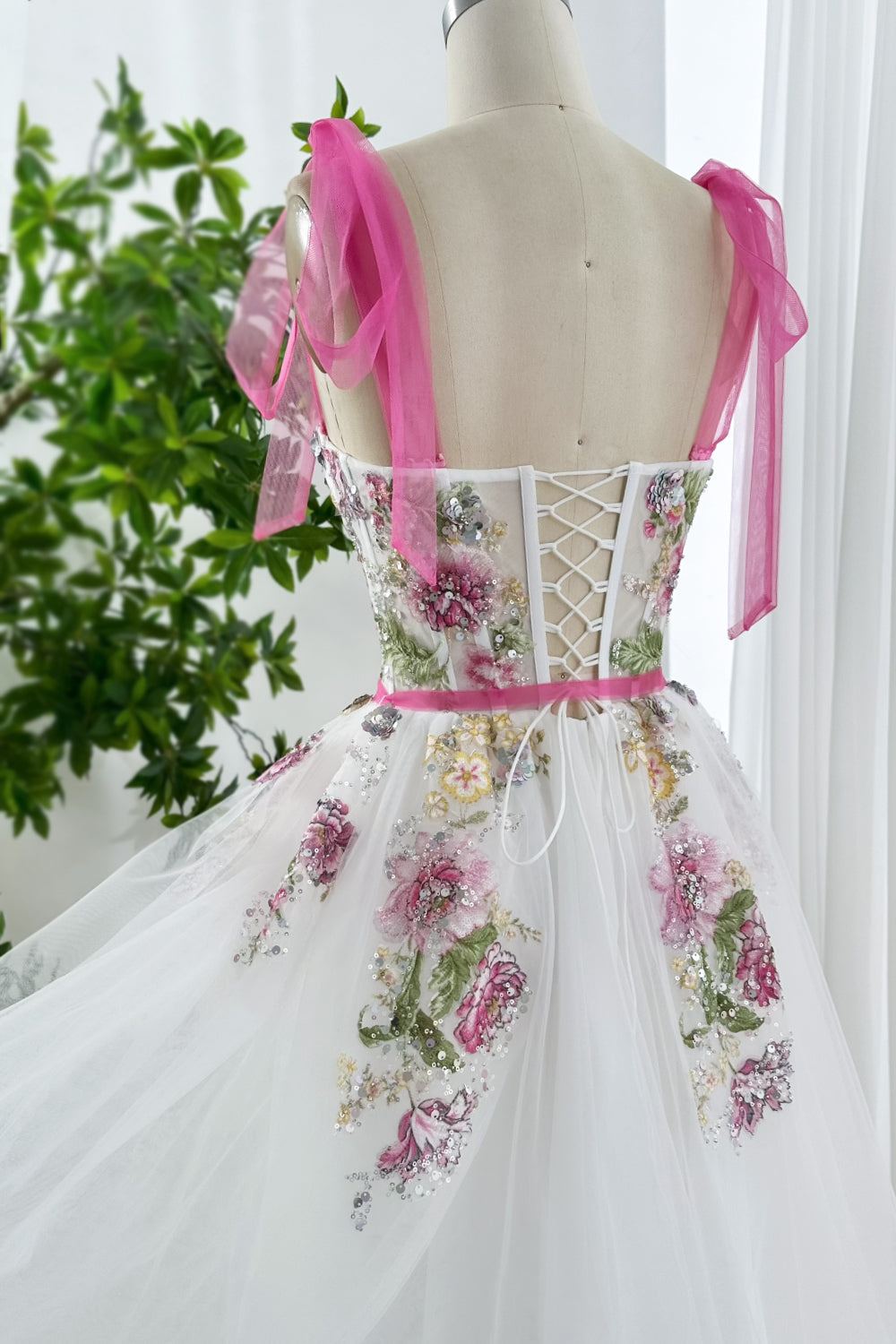 Fairytale inspired white gown with pink ribbon straps, floral applique embroidery, and layered tulle skirt shown back side