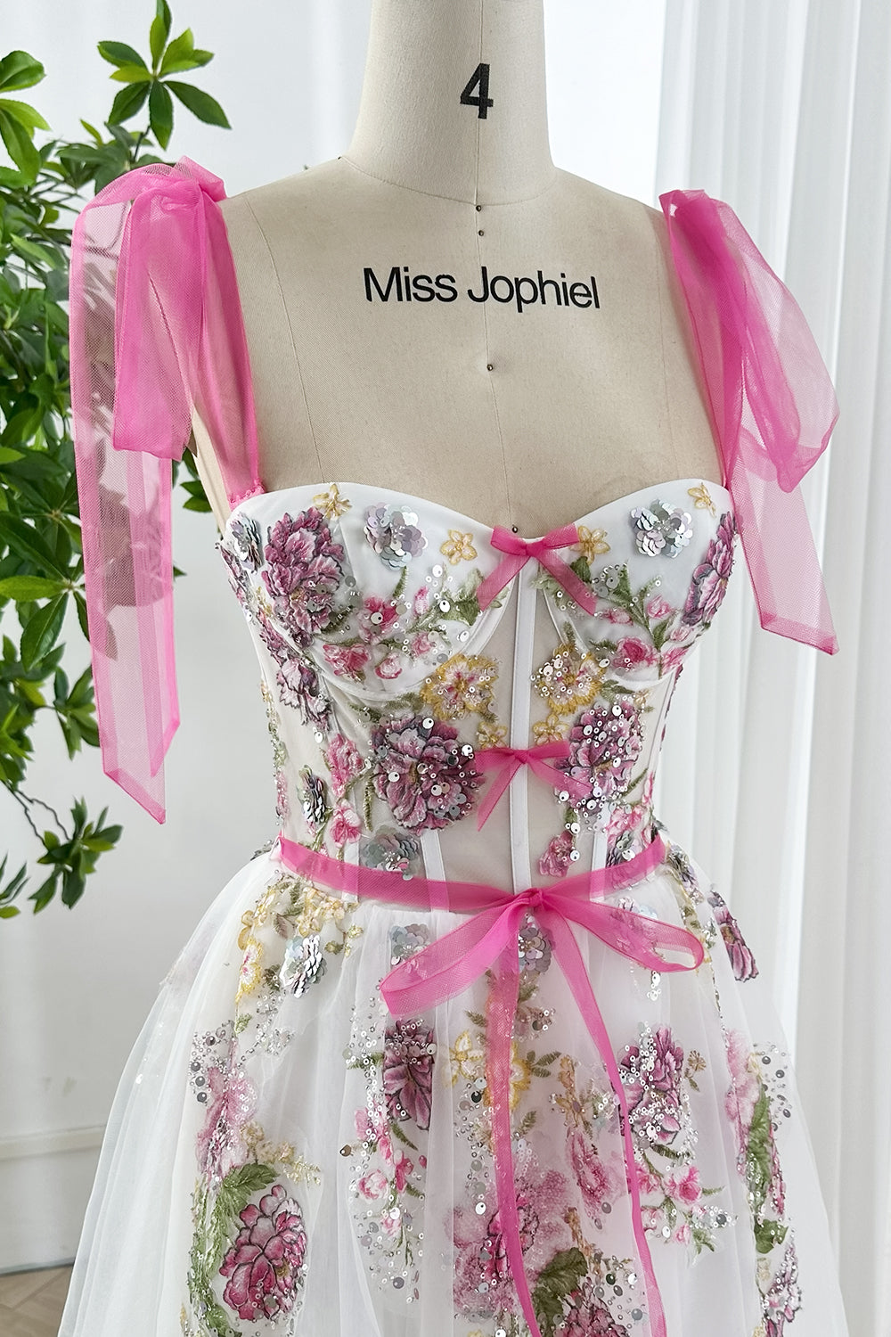 Garden party dress in white mesh with embroidered pink flowers, sequins, corset bodice, and tie straps shown front close up