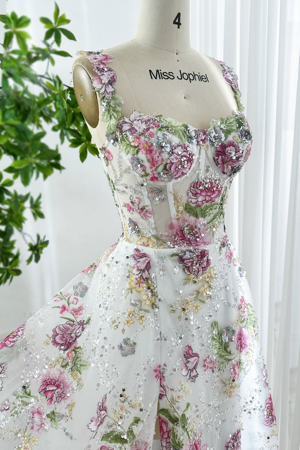 Romantic white floral embroidered gown with sequins, fitted corset bodice, sleeveless straps, displayed on mannequin Miss Jophiel brand