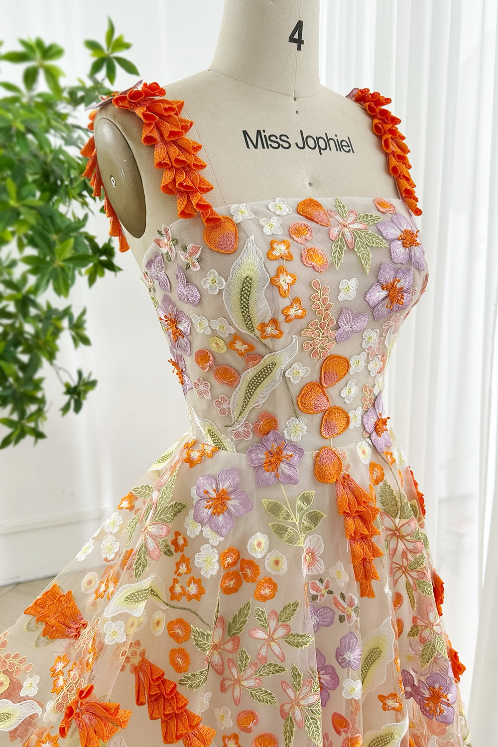 Square neckline embroidered mesh gown with vivid orange lilac blooms and 3D appliqué straps on mannequin Miss Jophiel