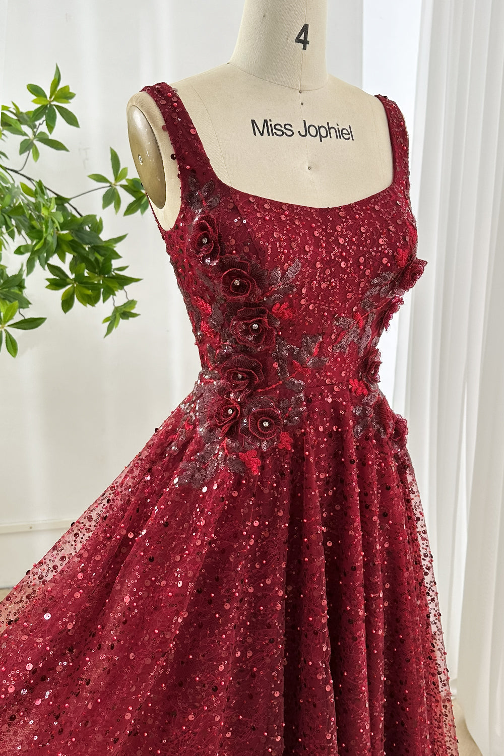 Bustier detail closeup displays beaded blossoms, layered petals, shimmering mesh, sculpted waistline, romantic couture texture on wine shade