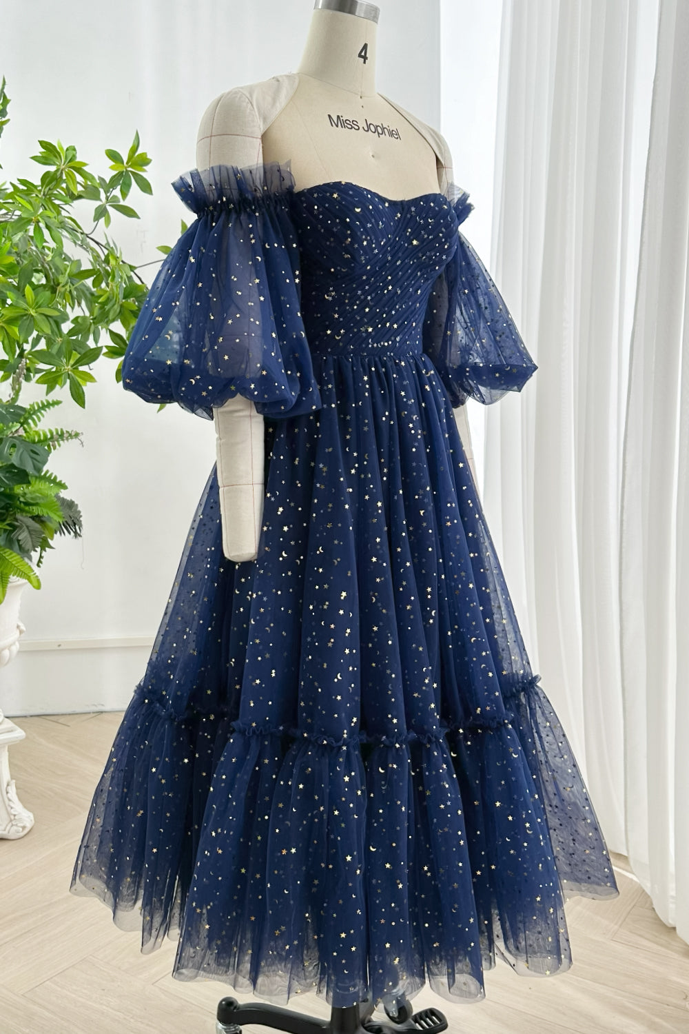 Deep navy tulle midi-length dress featuring metallic star print sweetheart neckline layered skirt and structured puff sleeve silhouette for evening wear