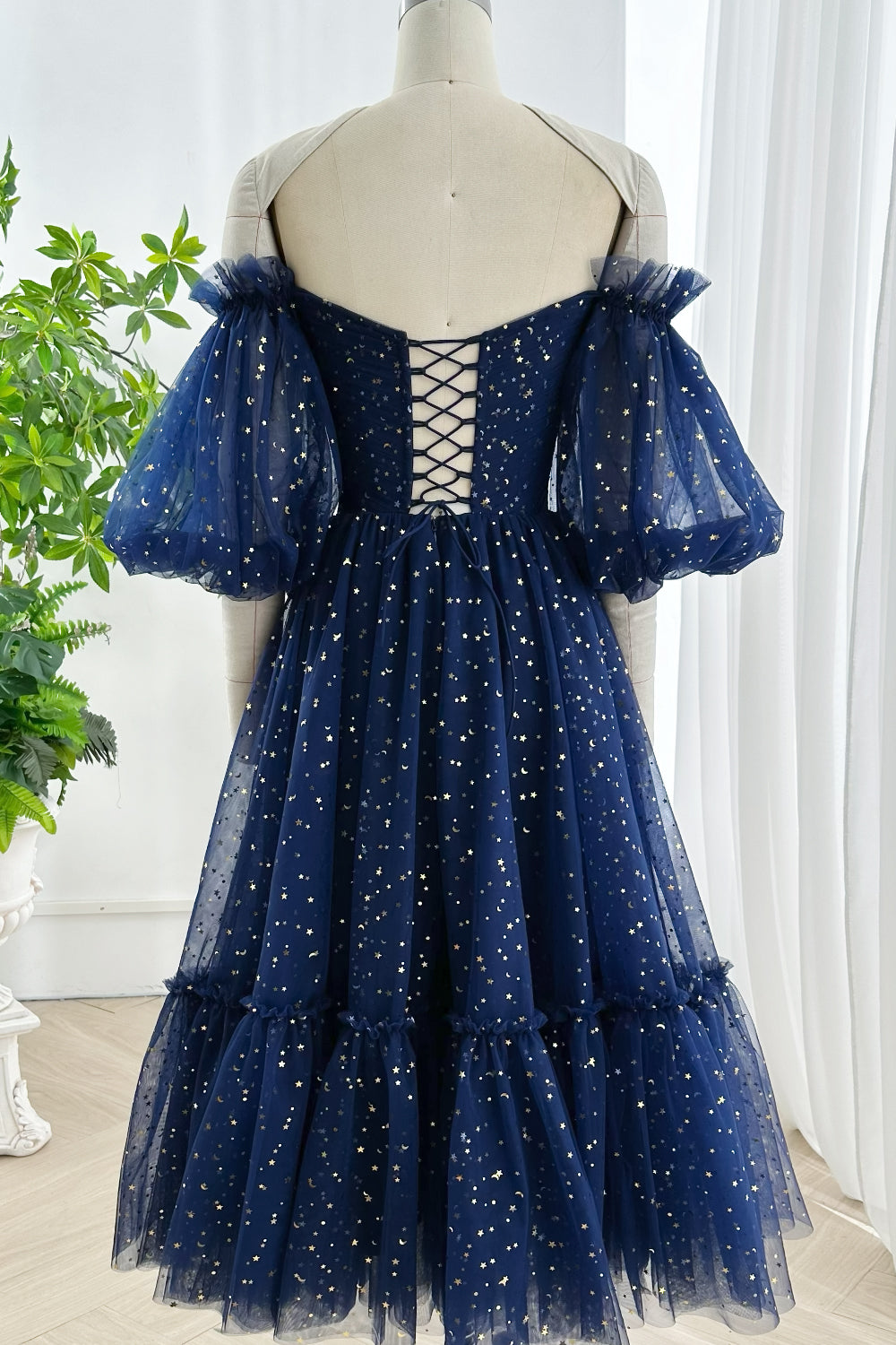 Romantic navy gown highlighted by lace-up back voluminous tulle puff sleeves and celestial metallic star print ideal for formal or evening celebration