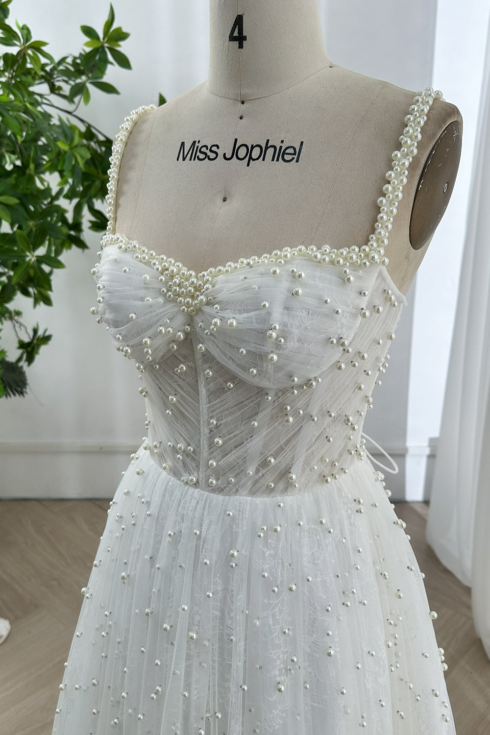 Close-up view of romantic pearl beaded sweetheart neckline and structured corset bodice with lace overlay and detailed stitching