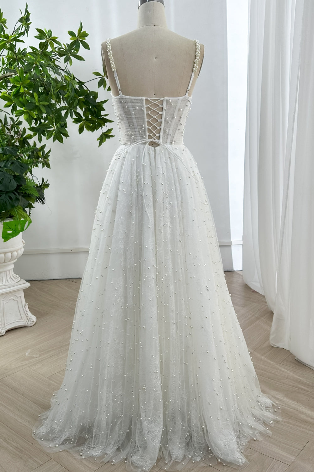 Back view of pearl beaded tulle gown with lace-up corset and full flowing floor-length skirt designed for bridal elegance