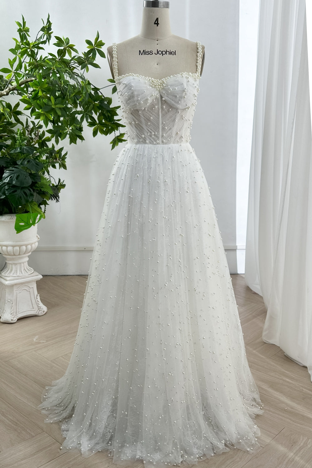 Ivory A-line wedding gown with pearl embellished tulle bodice and sweetheart neckline on mannequin, showcasing luxury craftsmanship