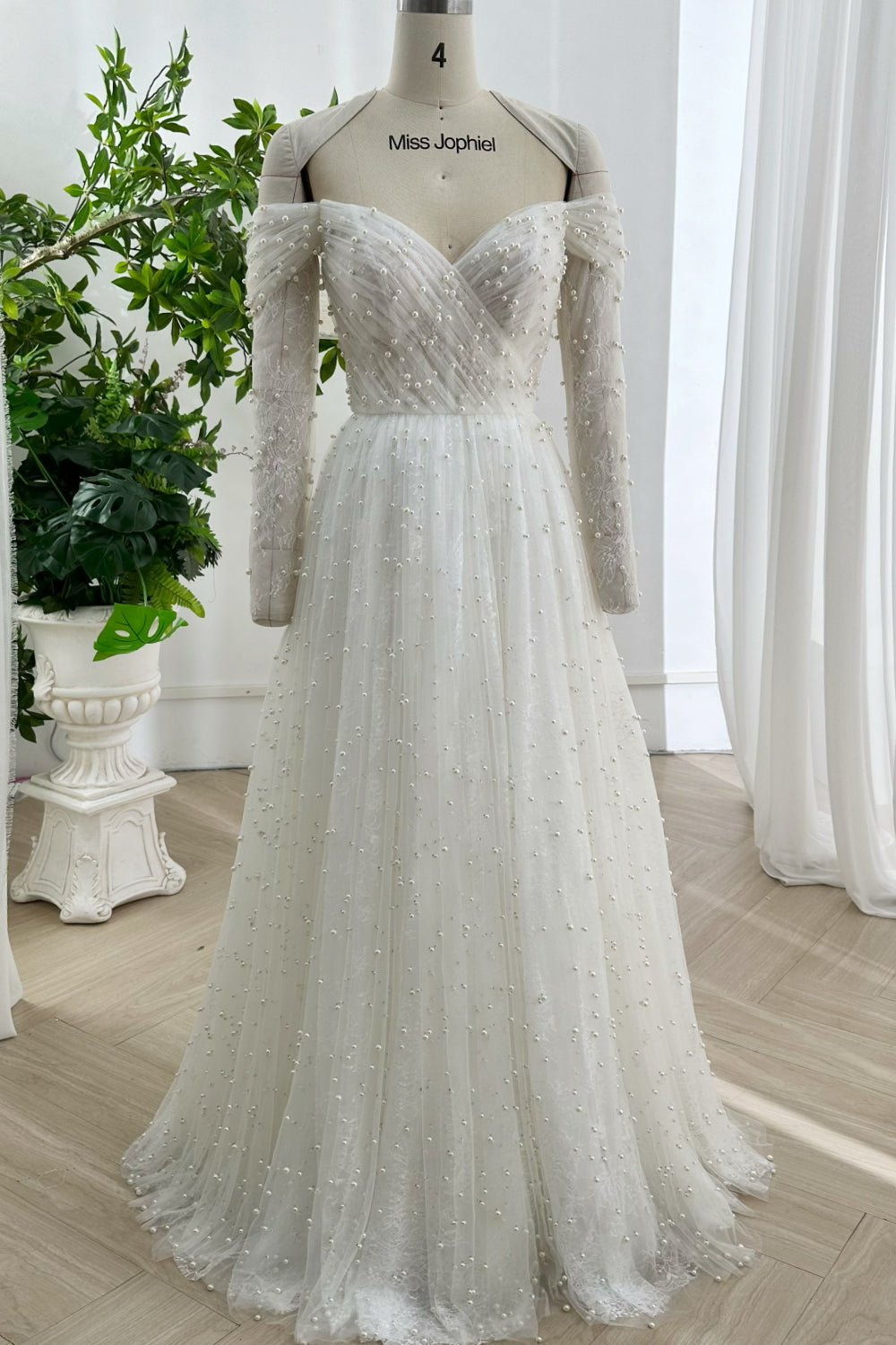 Romantic tulle bridal gown with long lace sleeves scattered pearls and elegant soft silhouette perfect for classic garden wedding events