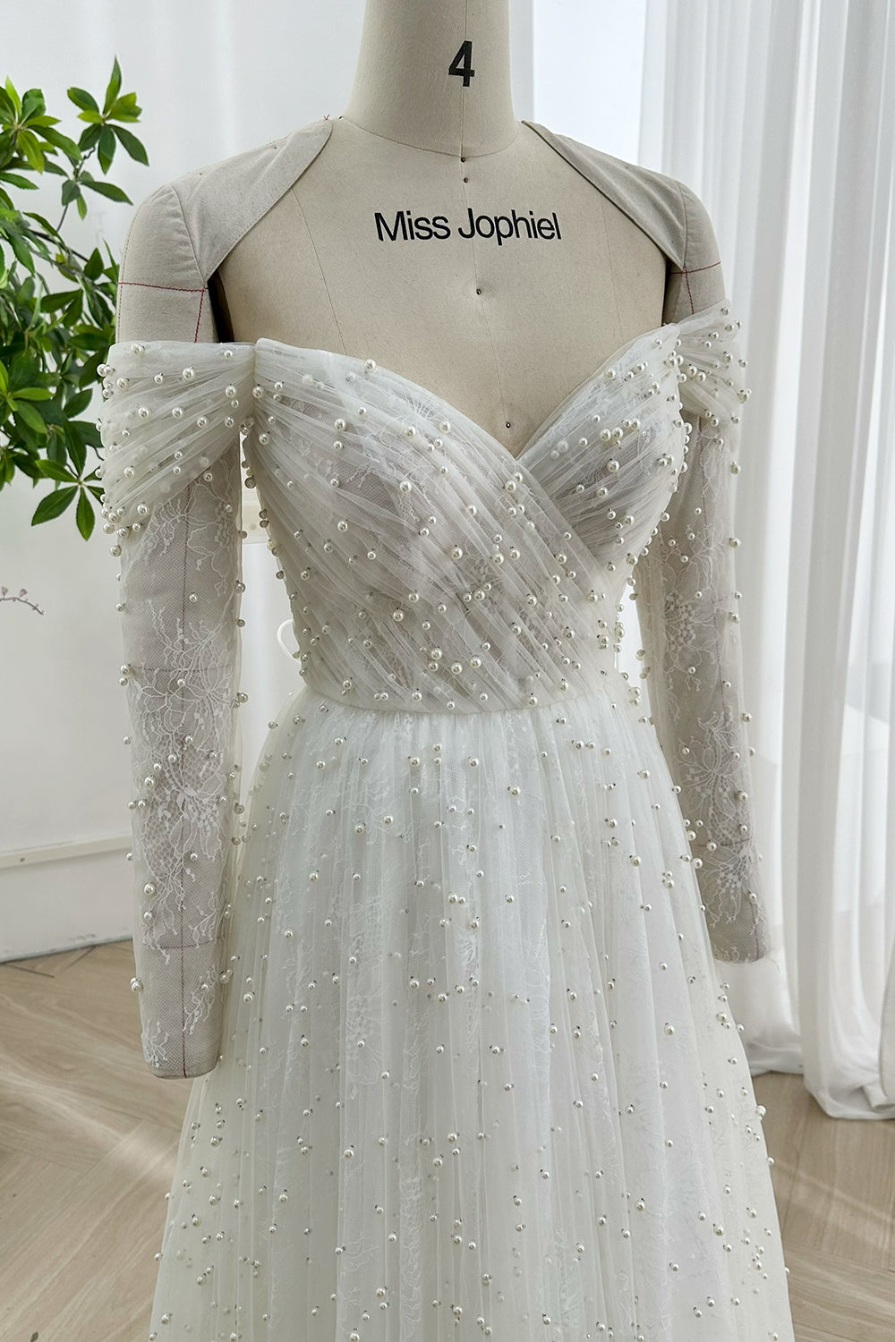 Classic lace pearl wedding dress featuring draped off-shoulder neckline delicate floral lace sleeves ideal for timeless sophisticated brides