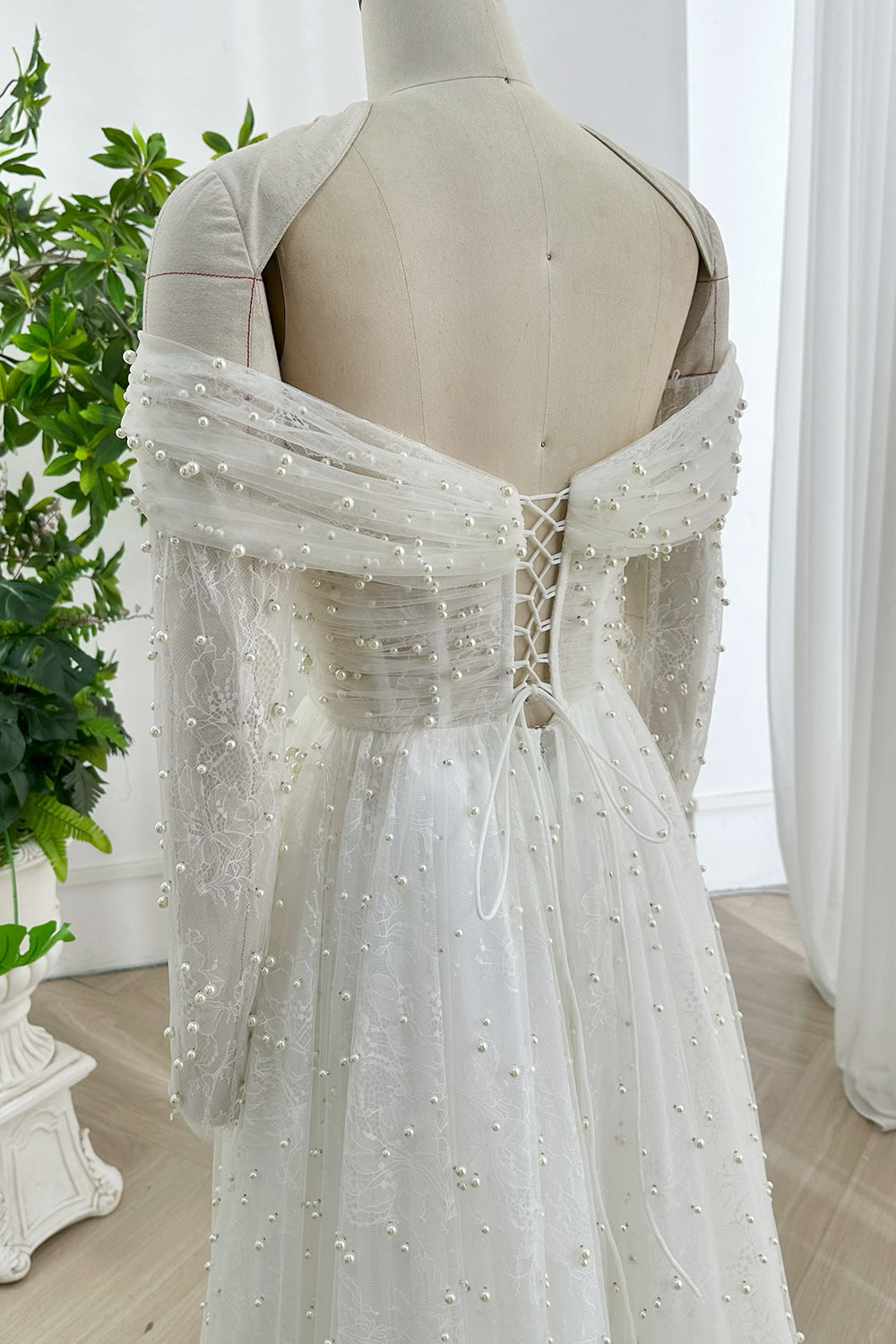 Vintage inspired pearl bridal dress with sheer lace long sleeves corset style bodice classic white tone flattering figure hugging waistline