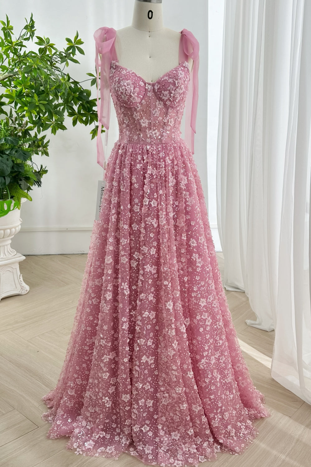 Blush pink long evening dress with floral appliques, sweetheart neckline, and flowing sequin tulle skirt in elegant studio lighting