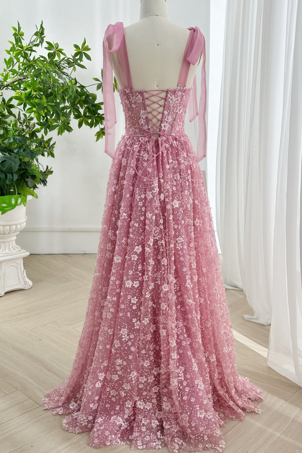 Pink lace-up back prom dress with floor length floral sequin skirt shown from rear view highlighting elegant ribbon tie detail