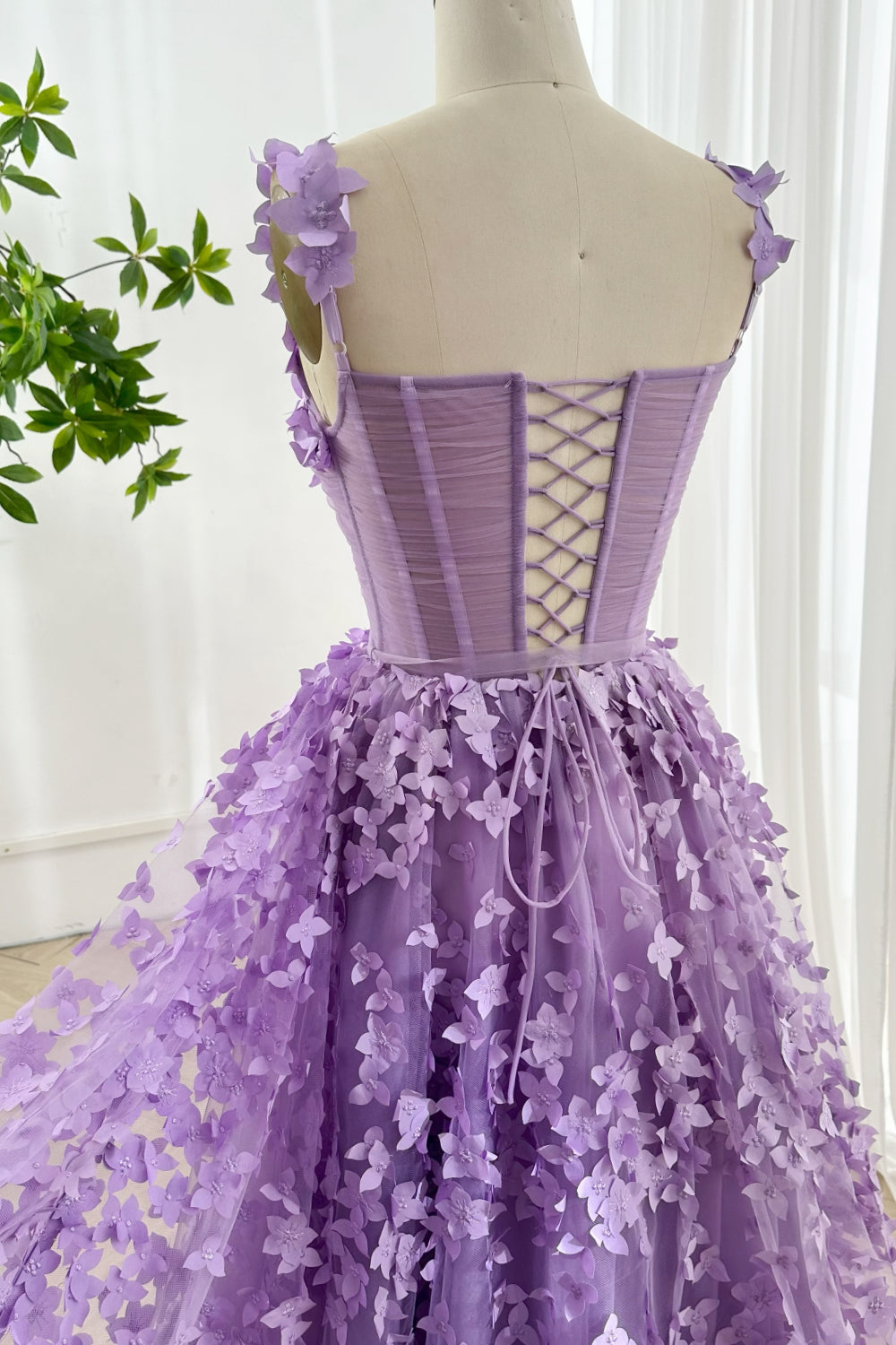 Rear angle of lavender floral gown displaying lace-up design delicate flower accents and ethereal skirt movement aesthetic