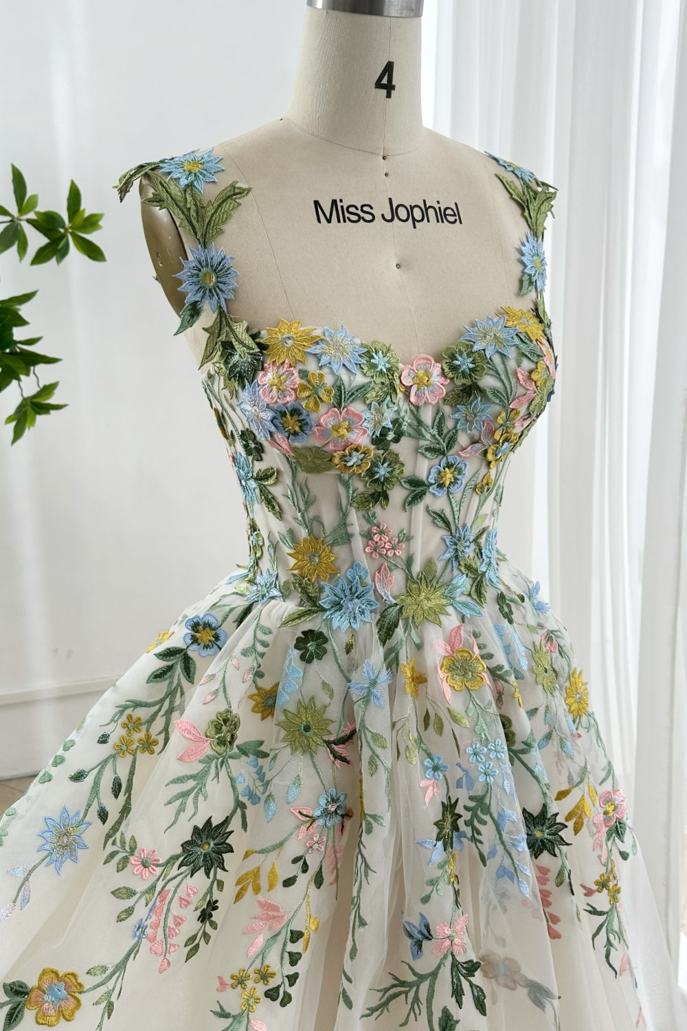 Close up of floral applique corset cocktail dress with multicolor embroidered flowers botanical themed fitted bodice in soft lighting
