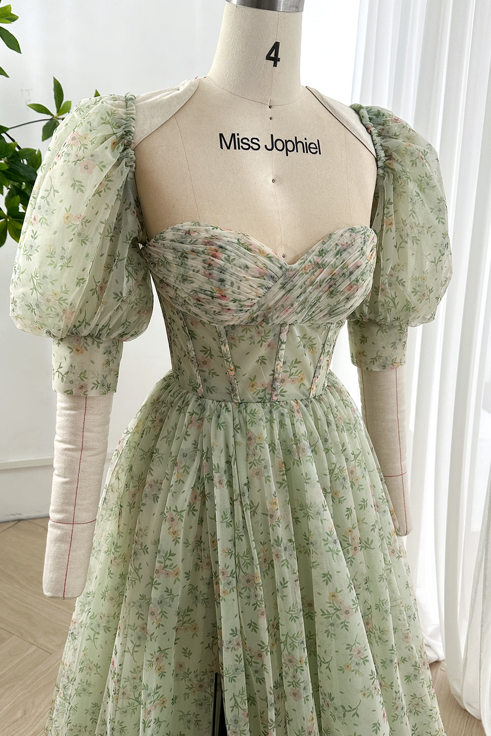 Vintage green tulle corset dress with boned bodice and ruched floral sweetheart neckline displayed on form in softly lit atelier