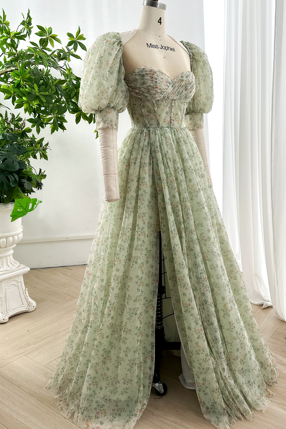 Elegant puff sleeve floral maxi dress in pale green fabric showcased side view highlighting flowing skirt and delicate garden motif