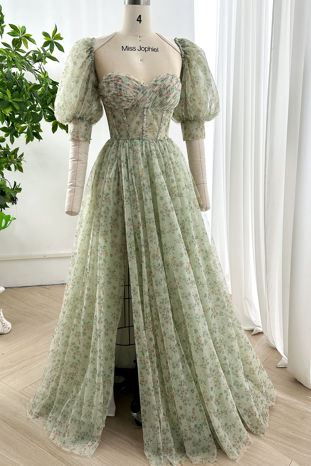 Romantic sage green floral corset gown with sweetheart neckline and puff sleeves on mannequin in sunlit studio for elegant garden styling