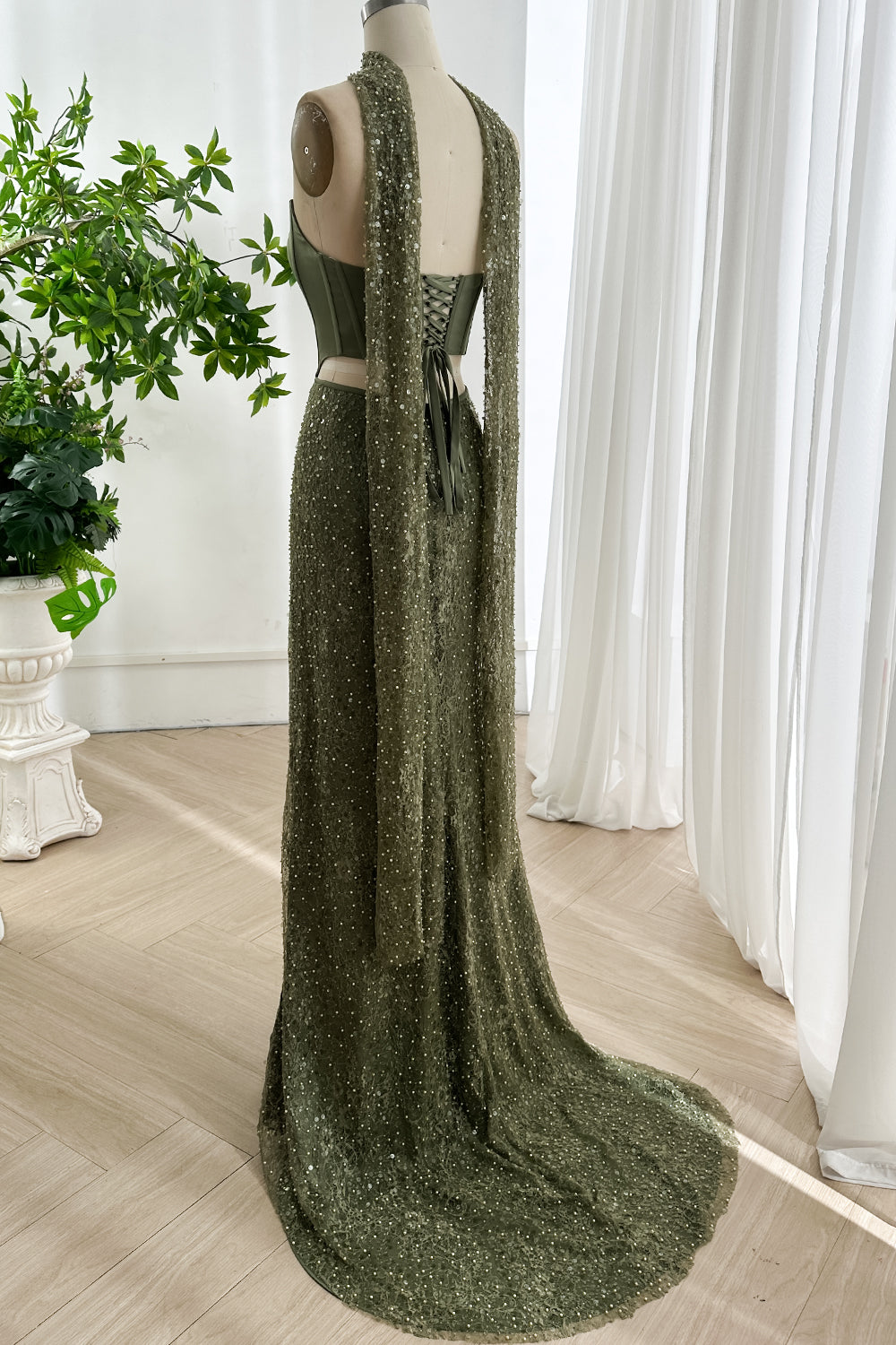 Back view of olive green two piece evening gown showing lace up corset closure and beaded skirt with flowing train