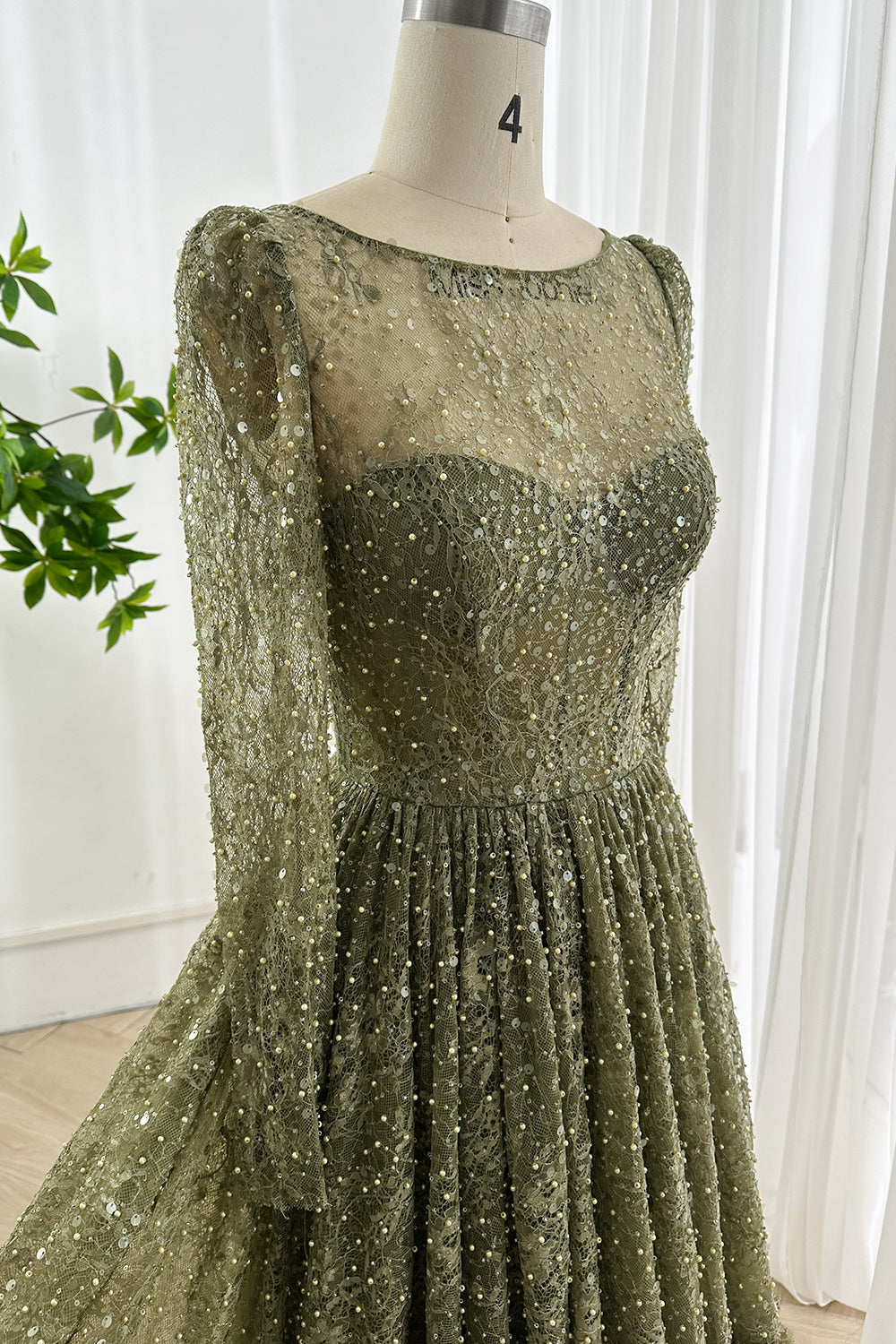 Close up of sheer illusion bodice showing intricate olive sequin lace embroidery fitted waist and delicate transparent fabric texture