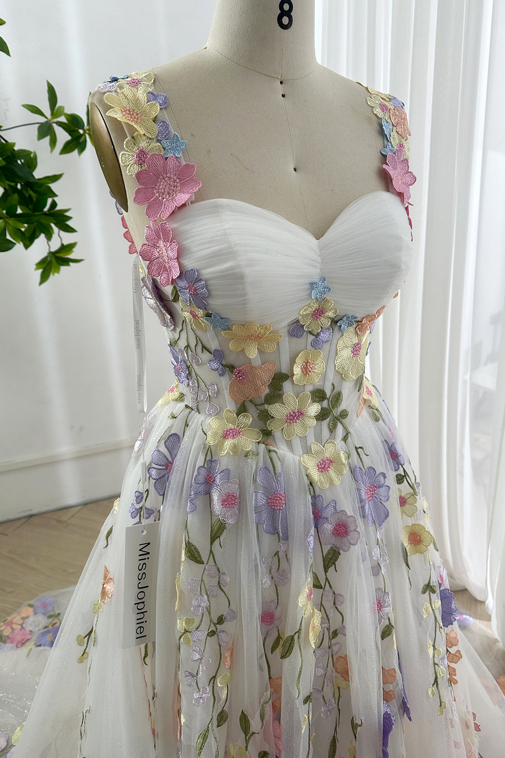 Close-up of glitter floral embroidered bodice showing sweetheart neckline and pastel 3D appliqués on shimmering tulle fabric