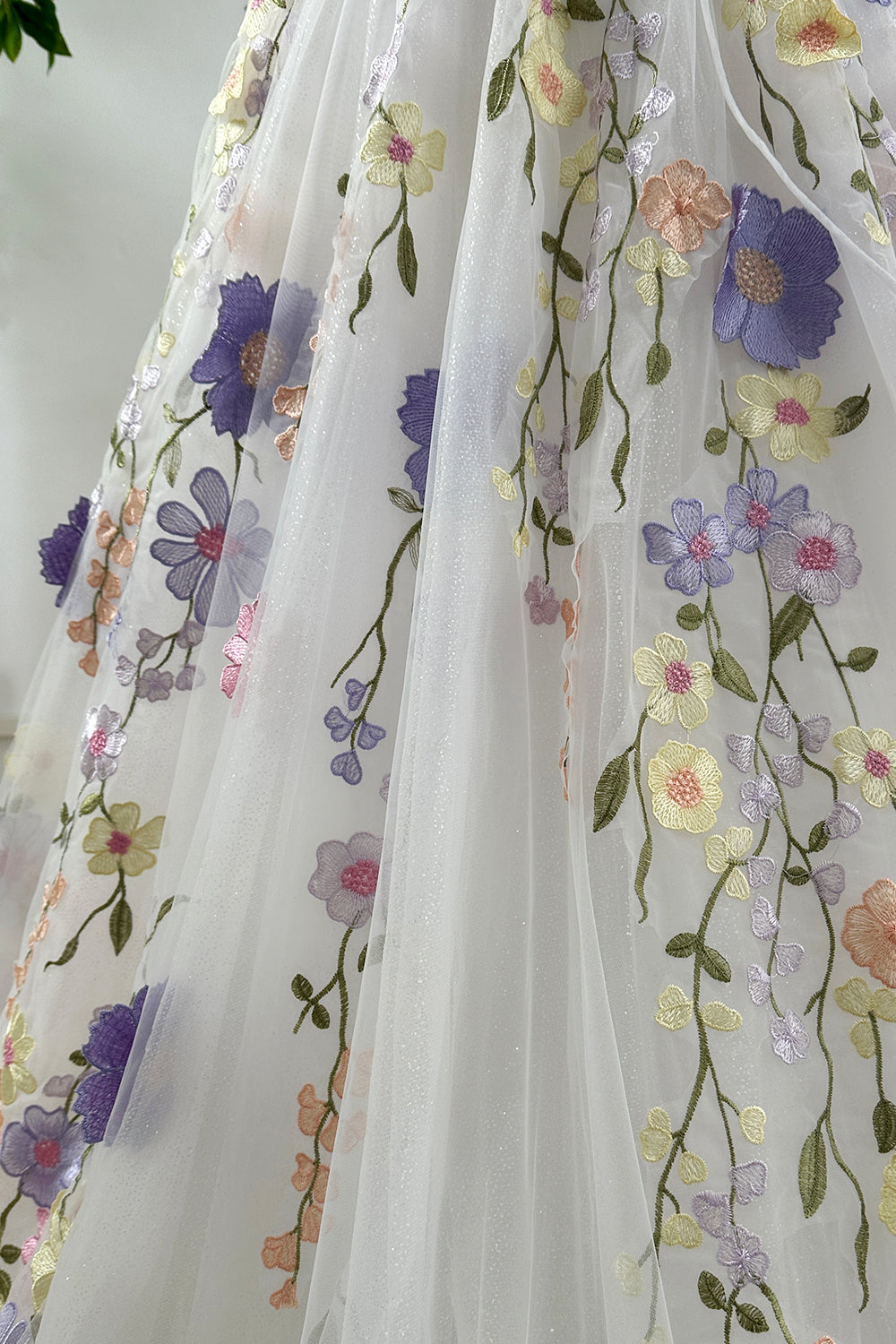 Close-up showing glittering tulle fabric and pastel 3D floral embroidery detailing for luxury sparkling evening dress