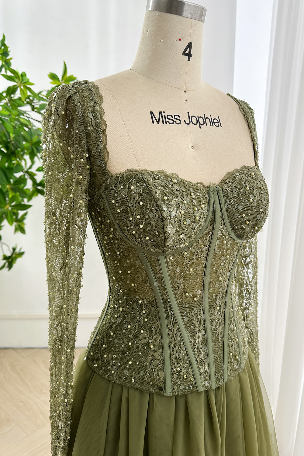 Close-up of forest green lace corset bodice with sequins and pearls showing fine boning details and sweetheart neckline
