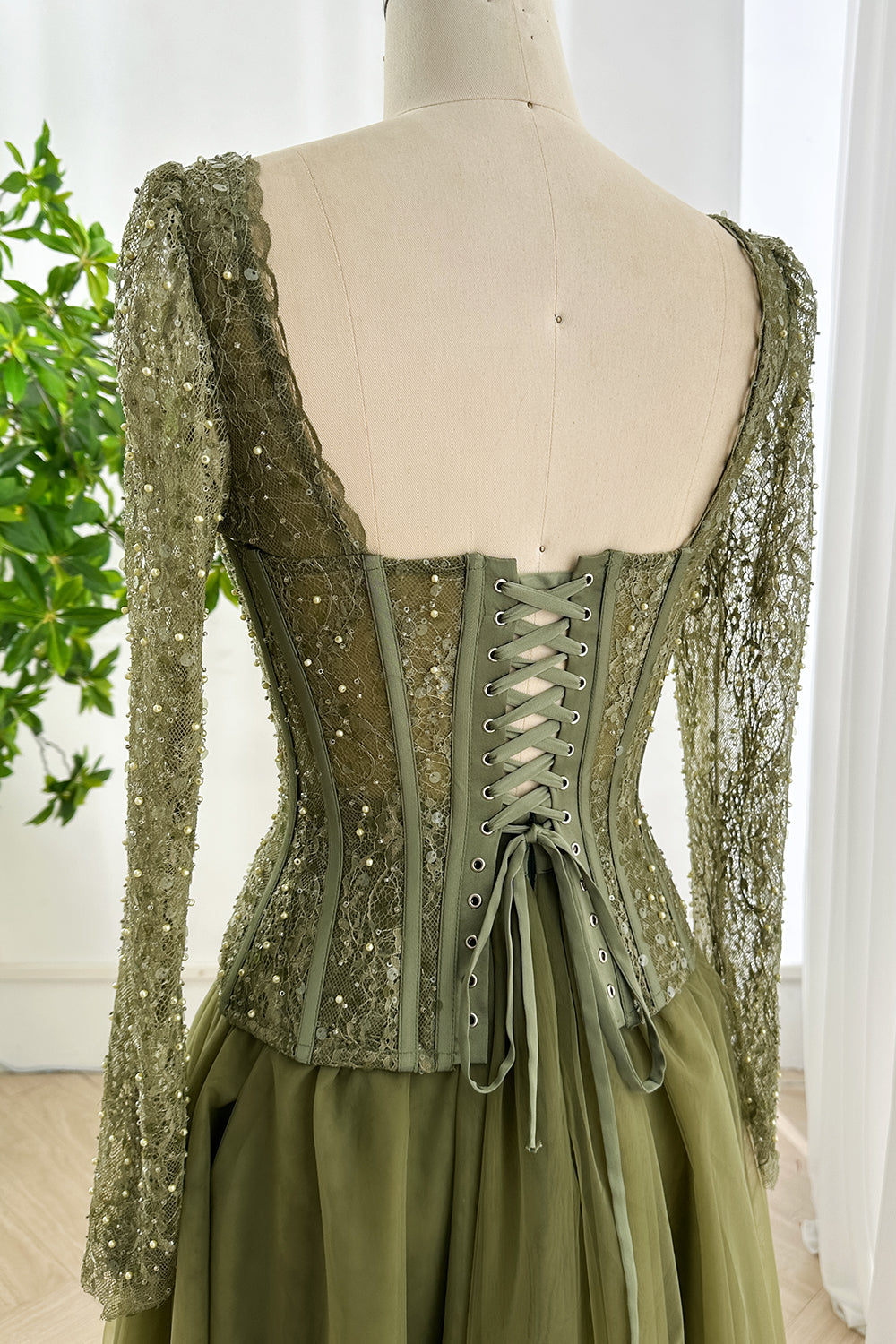 Back view showing lace up closure of olive green corset dress with sequin lace fabric and fitted long sleeves