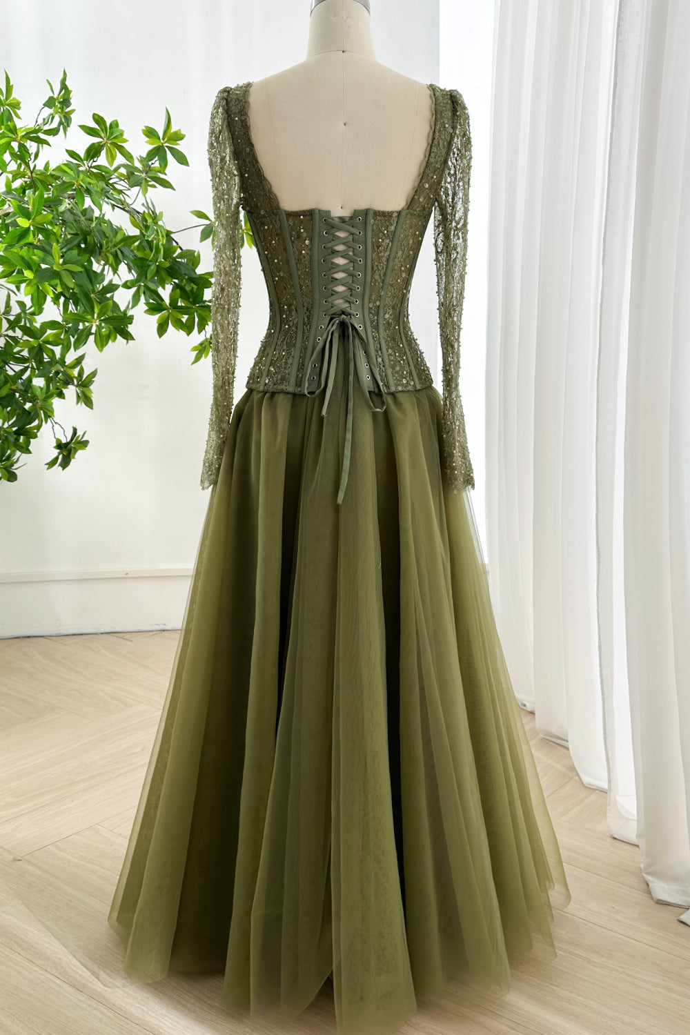 Elegant olive lace corset gown photographed from behind highlighting lace-up back and full length layered tulle skirt
