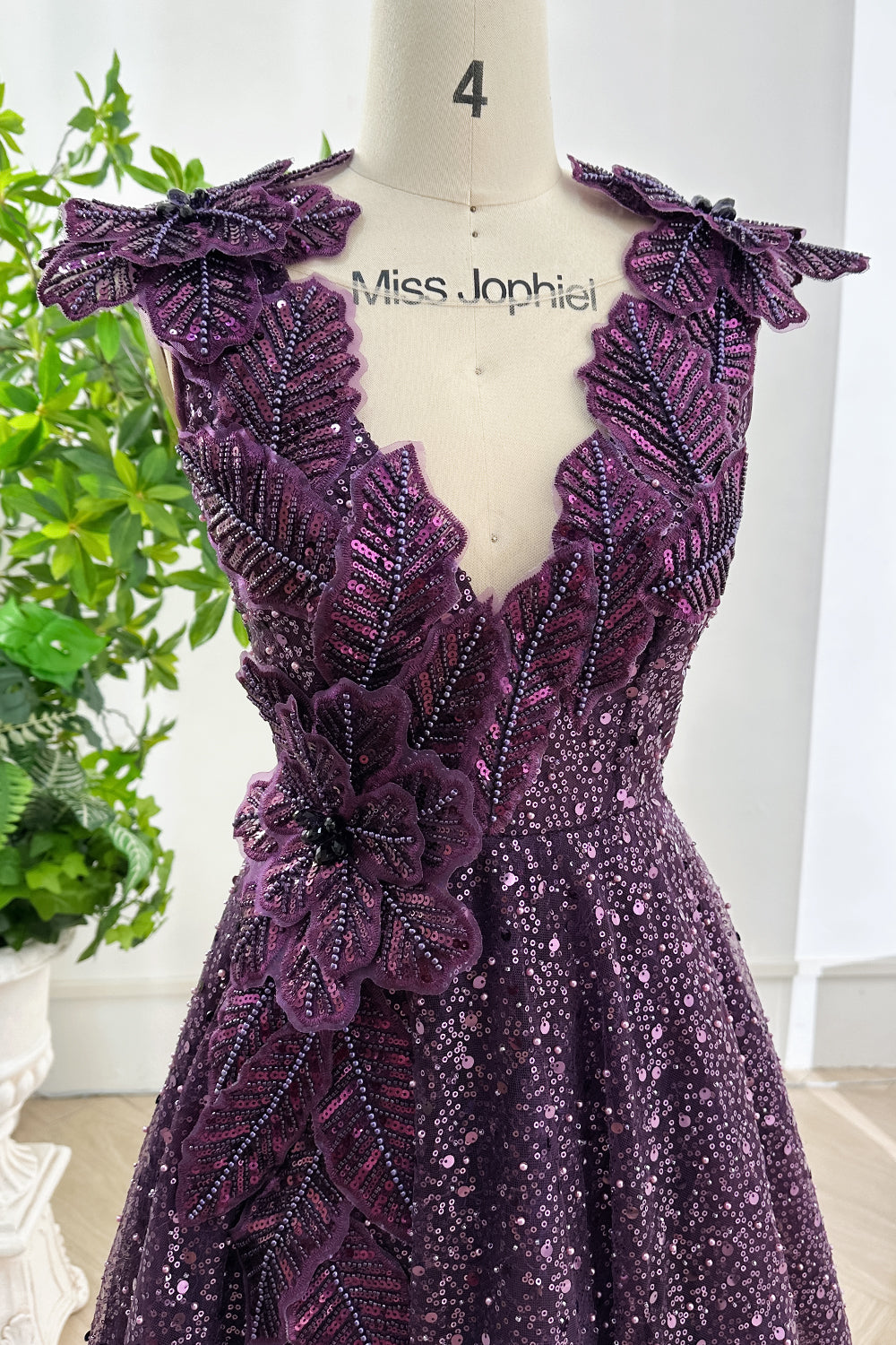 Close up of bodice showing detailed purple floral embroidery with shimmering sequins and structured V neckline craftsmanship